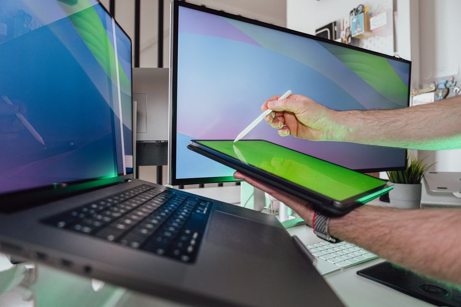 A person using a stylus on a tablet in a tech-savvy workspace