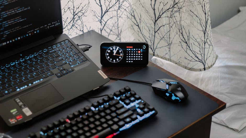 A modern workspace featuring a laptop, digital clock, and keyboard