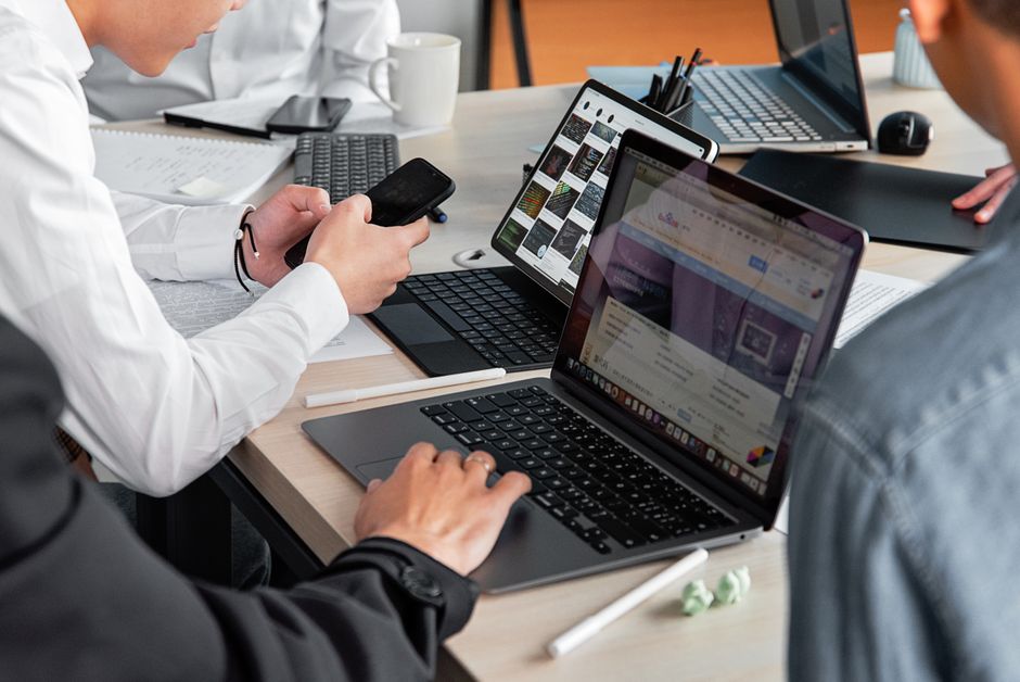 Professionals in a modern office discussing work with laptops